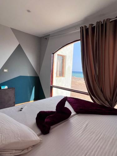 a bedroom with a bed and a window with the beach at Baywatch Camp in Nuweiba