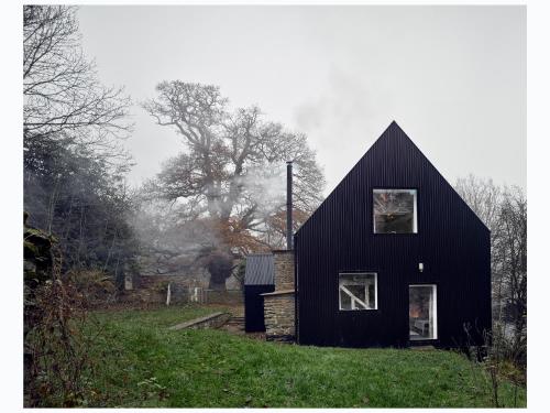 a black house sitting on top of a lush green field at Croft Lodge Studio in Leominster