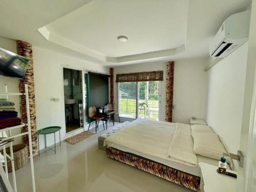 a bedroom with a bed and a desk and a window at Lee Red House Homestay in Ban Ao Yai