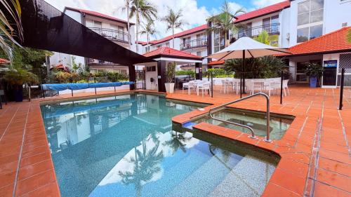 a swimming pool in a hotel with tables and umbrellas at Santana Resort Surfers Paradise in Gold Coast