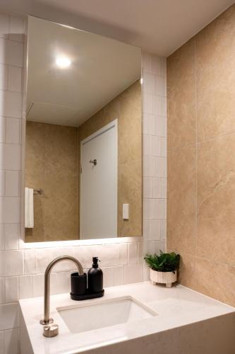 a bathroom with a sink and a mirror at Chada by Cadiz Properties - 2 Bedroom Apartment with Lakeview Pool, within CBD and Beside Commonwealth Park in Canberra