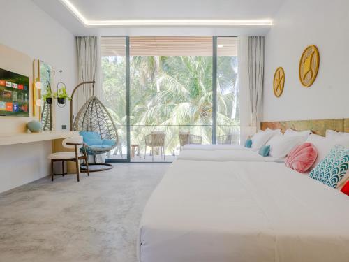 una camera da letto con un grande letto bianco e una grande finestra di Biosphere Beach a Dharavandhoo