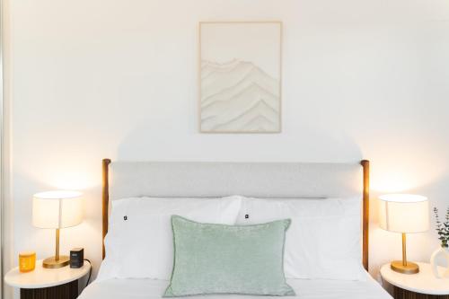a bedroom with a white bed with two lamps at Chada by Cadiz Properties - 2 Bedroom Apartment with Lakeview Pool, within CBD and Beside Commonwealth Park in Canberra