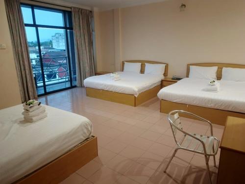 a room with two beds and a chair and a window at BB Hotel in Gerik