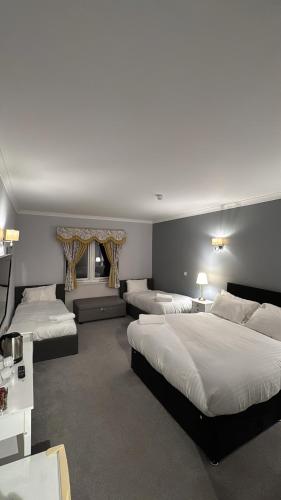 a hotel room with three beds and a television at Edinburgh West Residence in Edinburgh