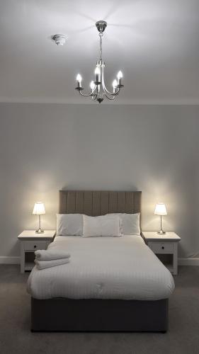 a bedroom with a bed with a chandelier and two tables at Edinburgh West Residence in Edinburgh