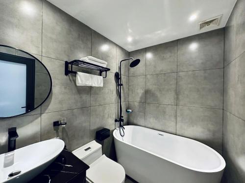 a bathroom with a tub and a toilet and a sink at LION 12 Hotel in Can Tho