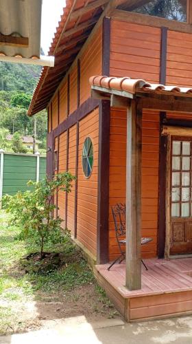 a wooden house with a chair on the porch at Cabana Jandaia in Teresópolis
