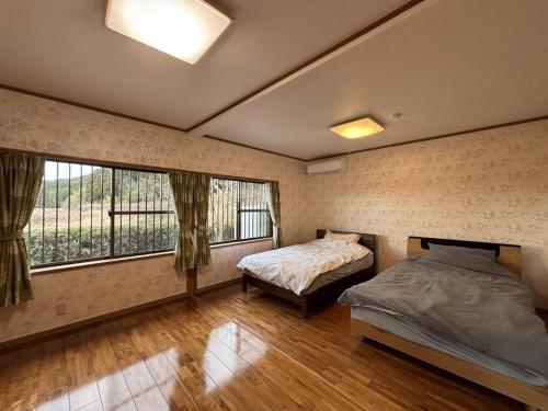 a bedroom with two beds and a large window at 蝶自来 in Yamaga