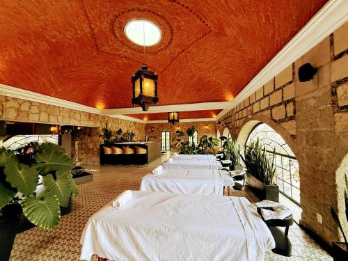 a row of white beds in a room with plants at Hacienda San Patricio in San Miguel de Allende