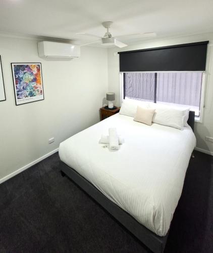 a bedroom with a large white bed with a window at No 3 Lakeside in Mulwala
