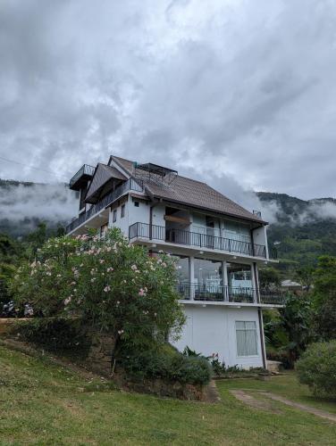 a large white house on a hill with a tree at Tranquil Edge Villa in Haputale