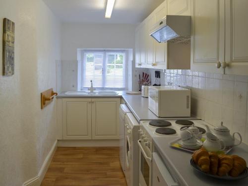 a white kitchen with a stove and a sink at Rosecraddoc Manor - Natalie Jane in Saint Cleer