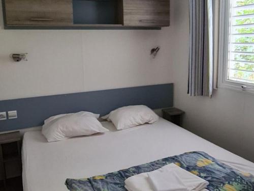 a bedroom with a bed with two pillows on it at Mobil-home 4 pers avec terrasse - API-1-52-1663 in Espira-de-Conflent