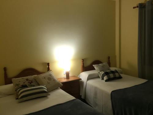 two beds in a room with a lamp on a table at La Fusteria del Casat in Sarroca de Bellera