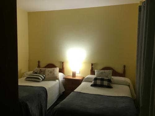 two beds in a room with a light on the wall at La Fusteria del Casat in Sarroca de Bellera