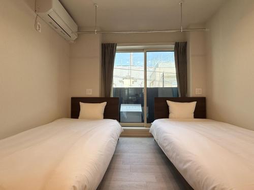 two beds in a room with a window at PRISM Inn Ikegami Kamata in Tokyo