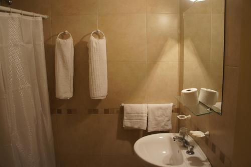 a bathroom with a sink and a shower with towels at Hotel Urca in Mar del Plata