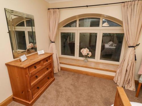 a bedroom with a dresser and a large window at Stable D'or in Alnwick
