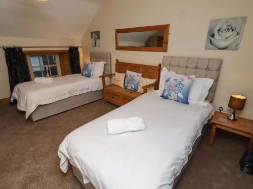a bedroom with two beds and a mirror at Stable D'or in Alnwick