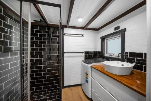 a bathroom with a white sink and a shower at Rural Oasis - Tiny Home 2BR Cabin & Outdoor Firepit Experience in Palmwoods