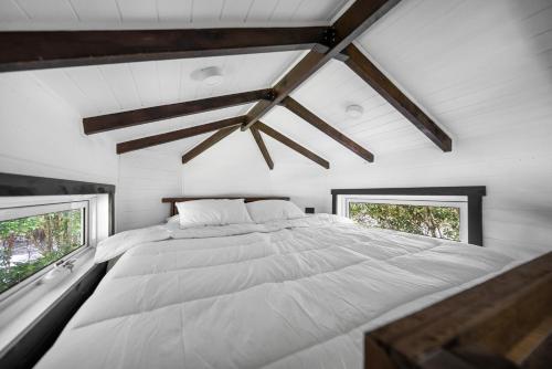 a large white bed in a room with two windows at Rural Oasis - Tiny Home 2BR Cabin & Outdoor Firepit Experience in Palmwoods