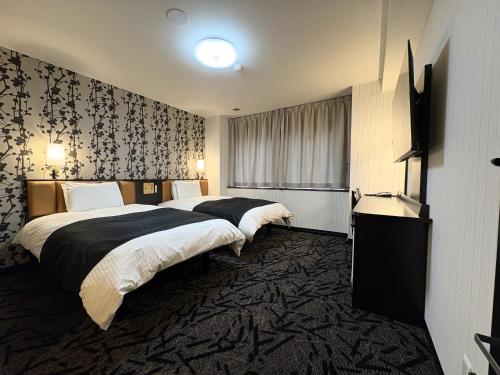 a hotel room with two beds and a television at APA HOTEL Fukushima Ekihigasi in Fukushima