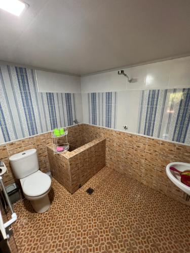 a bathroom with a toilet and a tub and a sink at Rote Surf Resort - Lualemba Bungalows in Nembrala