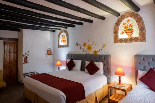 a bedroom with two beds and two windows at Hotel Spa Casa de Adobe Villa de Leyva in Villa de Leyva