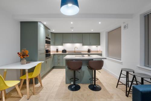 a kitchen with green cabinets and a table and chairs at Luxury Huddersfield Apartments & Prime City Centre Location & Opposite Train Station in Huddersfield