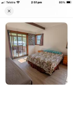 a bedroom with a bed in a room with a window at Beach house in Hallidays Point