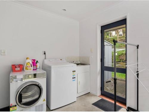 a laundry room with a washer and a washing machine at 3 bedroom home Tranquil Views in Rotorua