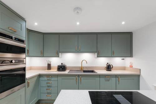 a kitchen with green cabinets and a sink at Luxury Huddersfield Apartments & Prime City Centre Location & Opposite Train Station in Huddersfield