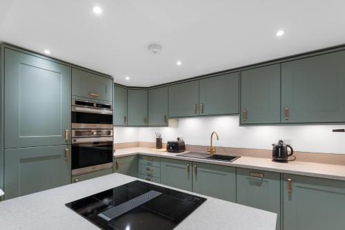 a kitchen with green cabinets and a counter top at Luxury Huddersfield Apartments & Prime City Centre Location & Opposite Train Station in Huddersfield