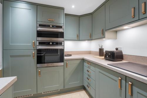 a kitchen with green cabinets and stainless steel appliances at Luxury Huddersfield Apartments & Prime City Centre Location & Opposite Train Station in Huddersfield