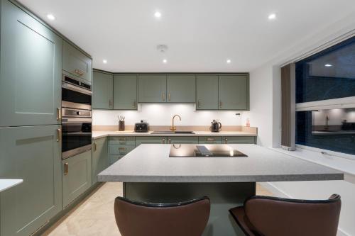 a kitchen with green cabinets and a large island at Luxury Huddersfield Apartments & Prime City Centre Location & Opposite Train Station in Huddersfield