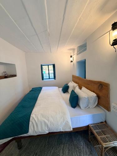 a bedroom with a large bed with white sheets and blue pillows at NAMOH e VIRAASAT in Chopta