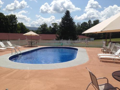 a swimming pool with chairs and umbrellas in a yard at Four Winds Country Motel in Manchester