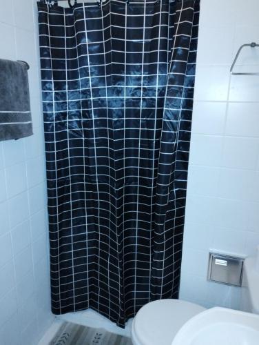 a bathroom with a black shower curtain and a toilet at Apartamento para duas pessoas com cama de casal in Teresópolis