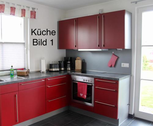 UmmanzにあるFischer's Ferienhaus Rügen mit Sauna und Kaminの赤いキャビネットと赤いコンロ付きのキッチン