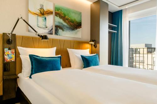 a hotel room with two beds and a window at Motel One Köln-Altstadt in Cologne