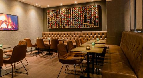 a restaurant with tables and chairs and a wall with books at Motel One Manchester-Royal Exchange in Manchester