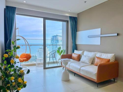 a living room with a couch and a large window at Căn hô The Song Du lịch Biển Tháp Tam Thắng Infinity Pool - Sophia Home in Vung Tau