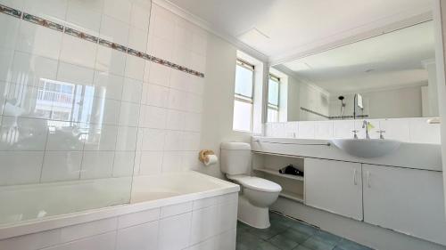 a white bathroom with a tub and a toilet and a sink at Santana Resort Surfers Paradise in Gold Coast