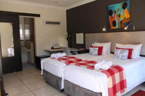 a bedroom with a large bed with red and white pillows at 3 Liebeloft Guest House in Edenvale