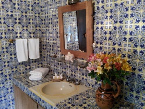 a bathroom with a sink with a mirror and a vase of flowers at La Casona Breakfast & Wellness Center in Temascaltepec de González