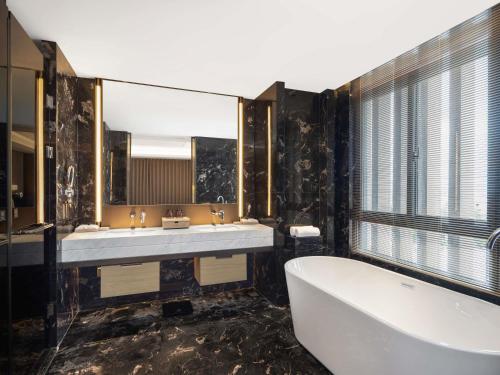 a bathroom with a tub and two sinks and a bath tub at Pullman Taizhou Shenxianju in Xianju
