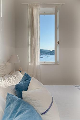 ein Schlafzimmer mit einem Bett mit Kissen und einem Fenster in der Unterkunft Villa Riva, Vis in Vis
