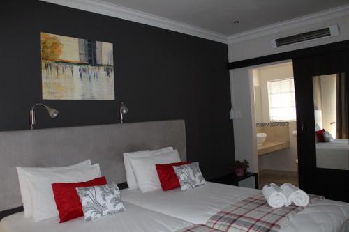 a bedroom with a bed with red and white pillows at 3 Liebeloft Guest House in Edenvale