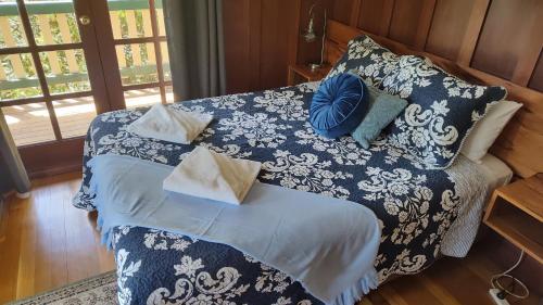 a bed with a blue and white blanket and pillows at Bridgefield Guest House in Margaret River Town